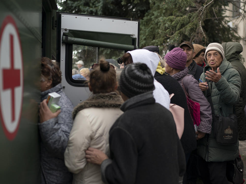 People wait in line as humanitarian aid is distributed at the recaptured town of Lyman, Ukraine, Wednesday, Oct. 5, 2022.