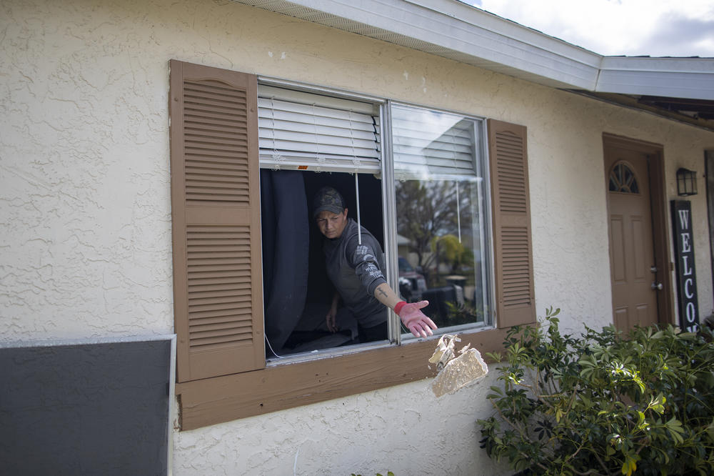 Tina Krasinski clears debris out of her mother's home in North Port, Fla., on Wednesday.