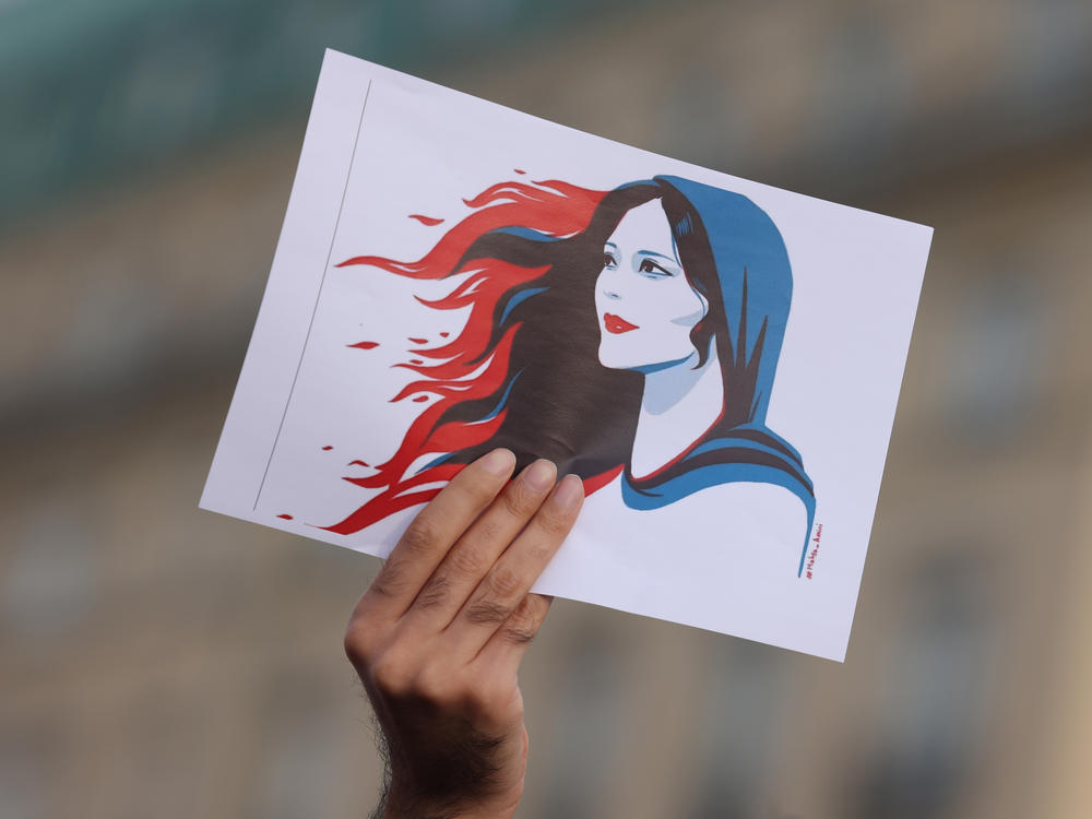 A protester holds a drawing of Mahsa Amini during a demonstration in Berlin, Germany, on Sept. 23. Amini was arrested by Iranian authorities in Tehran on Sept. 13 for not wearing her headscarf properly. She died three days later, apparently due to a severe head injury.