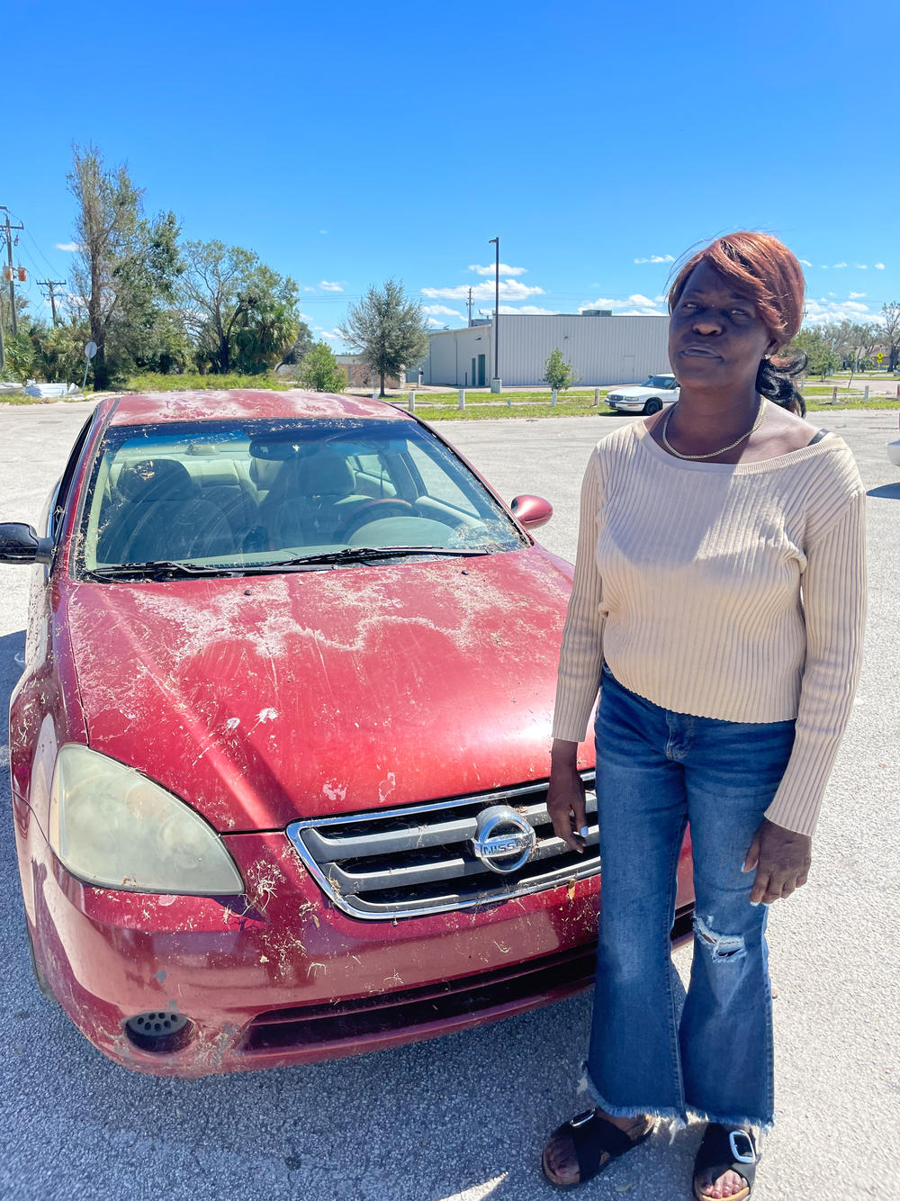 Virginia Hatcher Washington is seen next to the car she was sleeping in after Hurricane Ian tore through Arcadia, Fla. The Peace River was still flooding local highways several days after Ian.