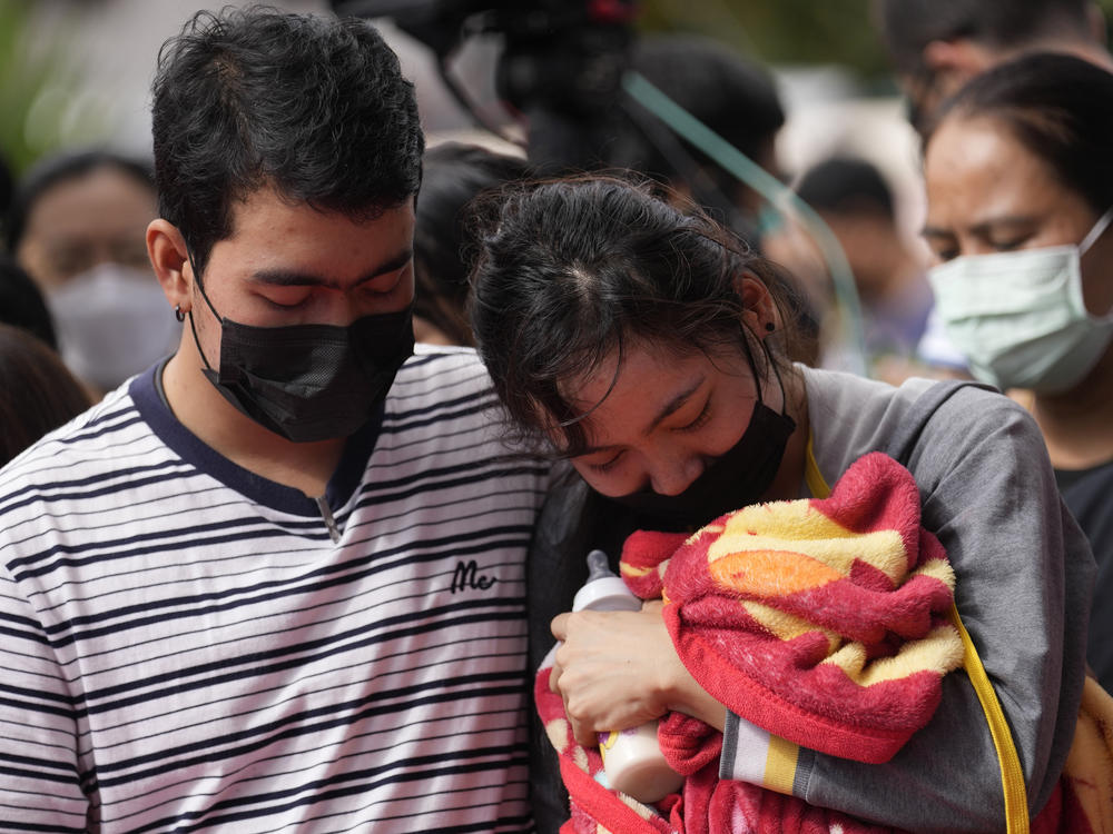 A family of a victim mourns as they bring a blanket and a milk bottle during a ceremony for those killed in the attack on the Young Children's Development Center in the rural town of Uthai Sawan, north eastern Thailand, Friday, Oct. 7, 2022.
