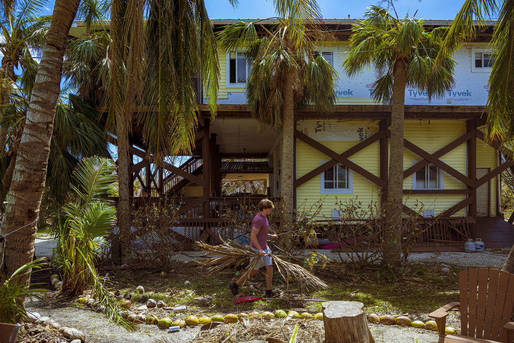 Jake Day cleans up part of his home that was damaged in Hurricane Ian on Little Gasparilla Island, Fla.