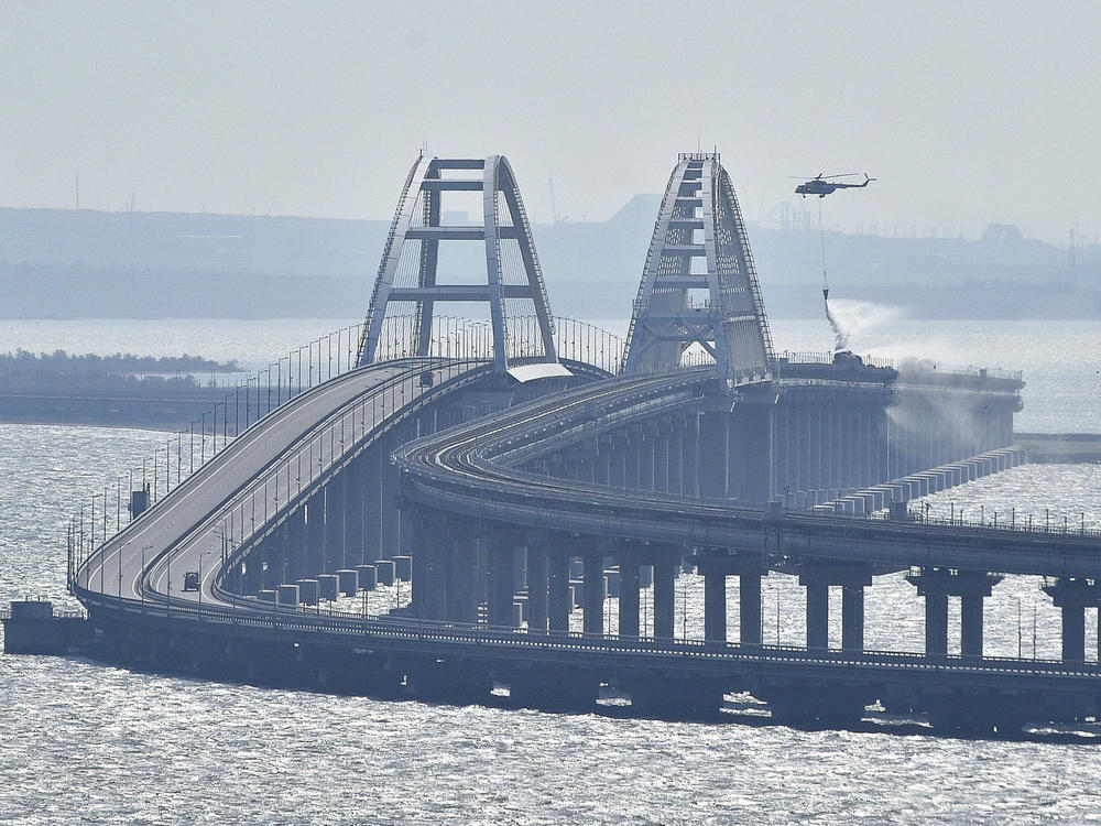 A helicopter drops water to stop fire on Crimean Bridge connecting the Russian mainland and Crimean peninsula over the Kerch Strait on Saturday.