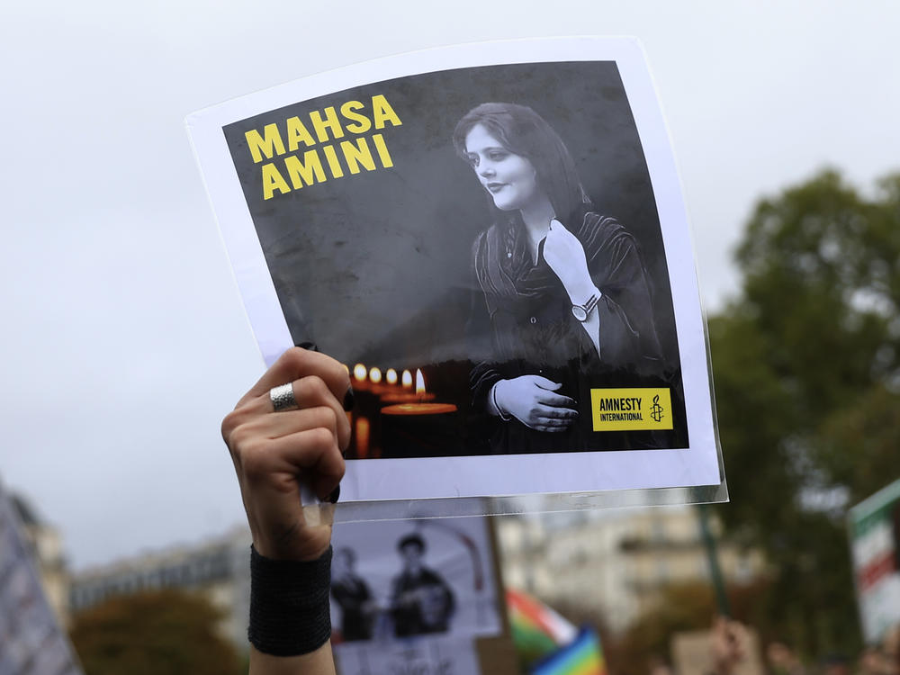 A protester shows a portrait of Mahsa Amini during a demonstration to support Iranian protesters standing up to their leadership over the death of a young woman in police custody, Sunday, Oct. 2, 2022 in Paris.