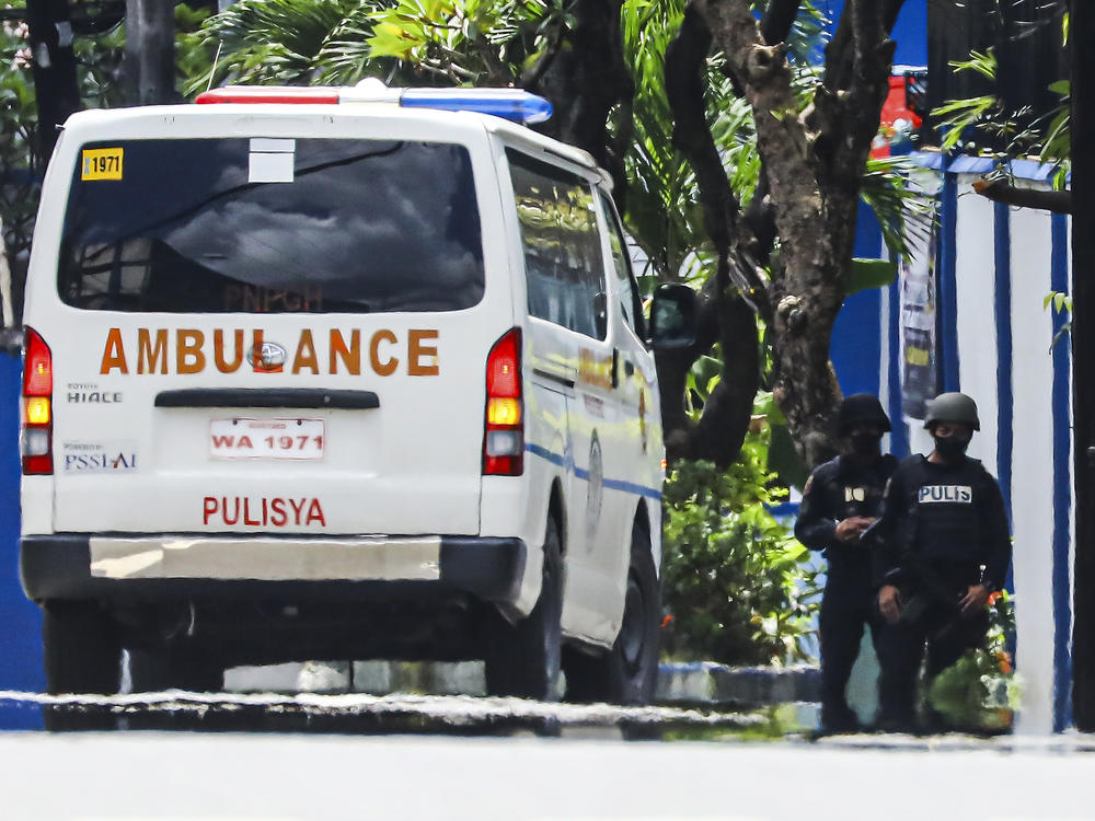 Police keep watch as an ambulance is parked outside the PNP Custodial Compound in Camp Crame police headquarters, Metro Manila, Philippines on Sunday Oct. 9, 2022.