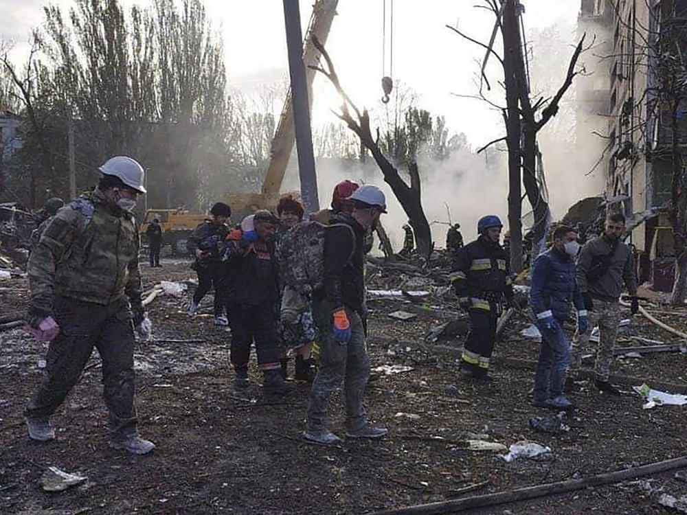 In this photo provided by the Ukrainian Emergency Service, rescuers work at the scene of a building damaged by shelling in Zaporizhzhia, Ukraine, Sunday, Oct. 9, 2022.