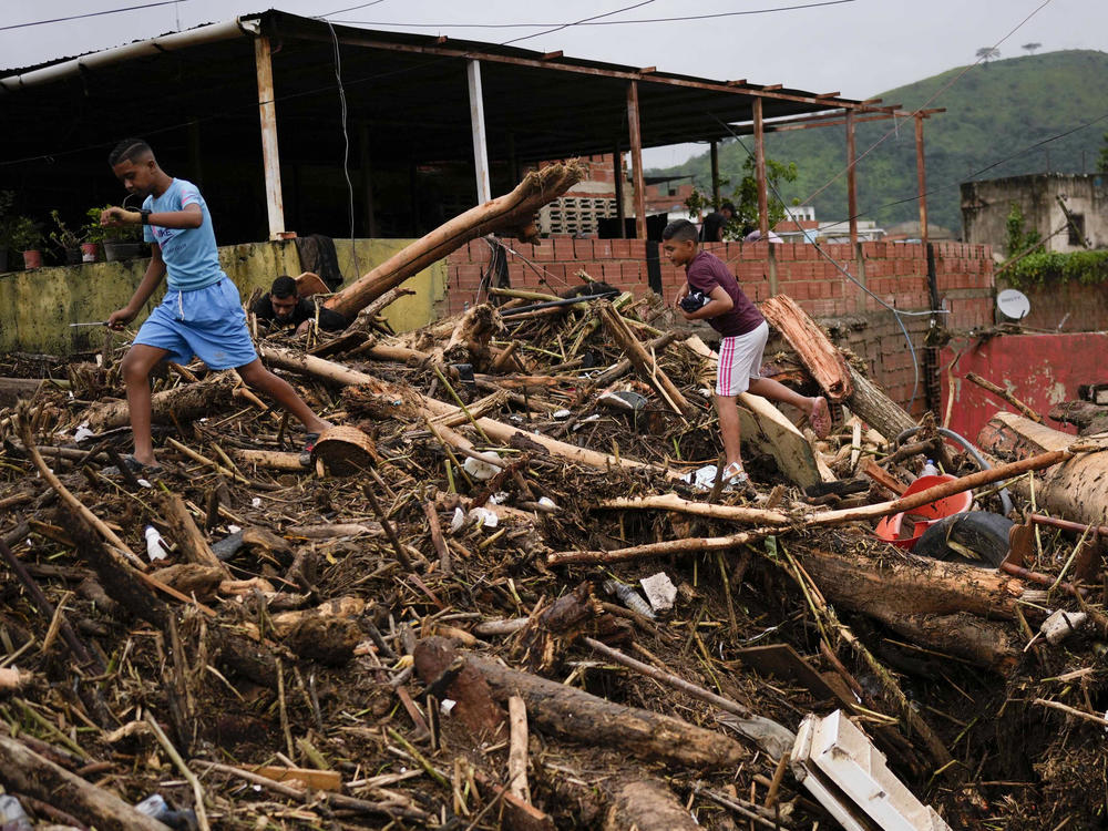 A boy carries sneakers he found amidst the rubble caused by flooding in Las Tejerias, Venezuela, Sunday, Oct. 9, 2022.