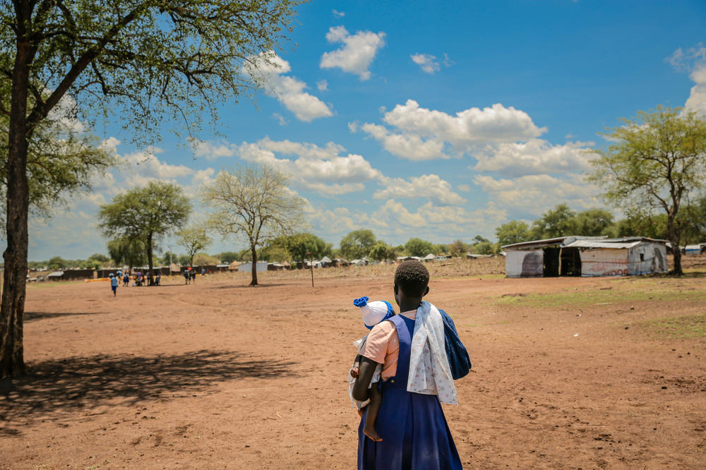 Carrying her 6-month-old baby, a 15-year-old walks home from school for her lunch break. She attends Romogi Primary School in Uganda's Palorinya Refugee Settlement. Back in session after the COVID lockdown, the school has 19 child mothers, including some girls who became pregnant while out of school. Studies indicate a global increase in teen pregnancy during the pandemic.