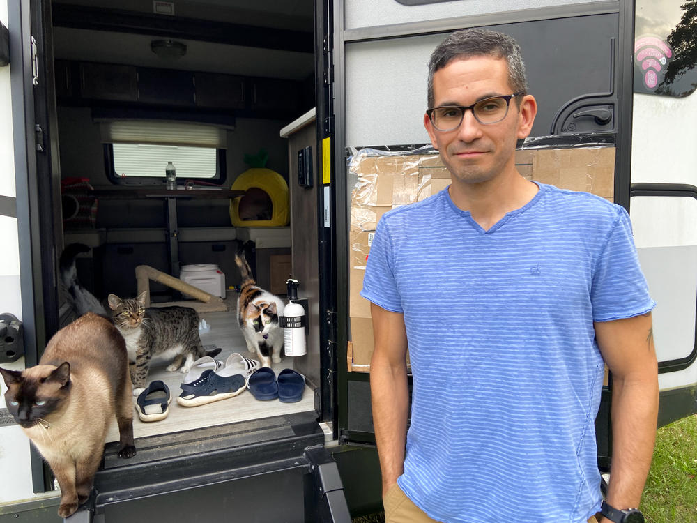 Mike Johansen stands by the door of the camping trailer where the couple is living while they wait for construction on their new home to be finished.