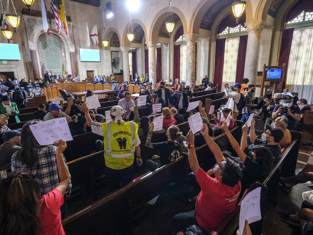 People hold signs and shout slogans as they protest before the cancellation of the Los Angeles City Council meeting Wednesday in Los Angeles.