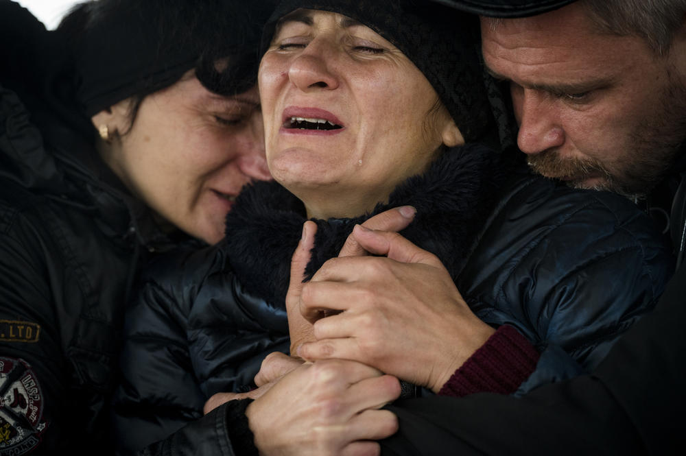 Iryna and Andriy Grycenko (center and right) mourn the death of their 11-year-old daughter, Anastasiya, at her funeral in Kharkiv on Sept. 20. At left is Iryna's sister, Anastasiya's aunt, Rimma Leiba.