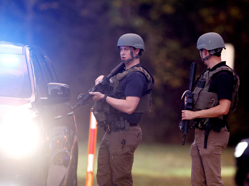 Law enforcement stand at the entrance to Neuse River Greenway Trail parking at Abington Lane following a shooting in Raleigh, N.C., Thursday, Oct. 13, 2022.