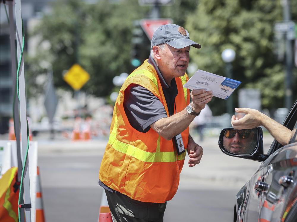 A voter hands over his ballot to an election judge at a drive-through ballot drop site in Denver on June 28, 2022. State election authorities accidentally sent voter registration information to 30,000 non-citizens who are ineligible to vote, which has fed conspiracy theories about the upcoming midterms.