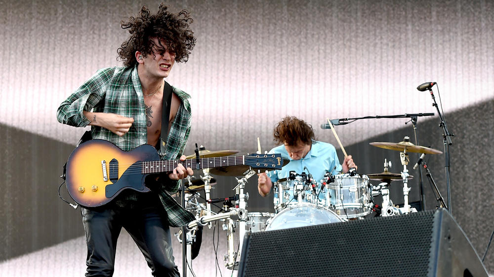 Healy (with guitar) and drummer George Daniel onstage during the 2016 Coachella Valley Music & Arts Festival.