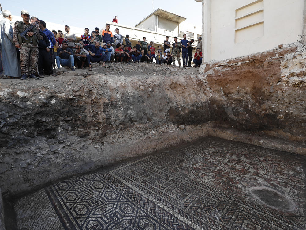 People look at a large mosaic that dates back to the Roman era in the town of Rastan, Syria, on Wednesday.