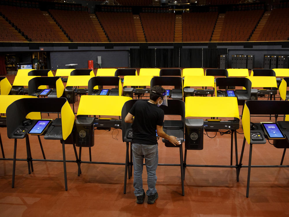 A poll worker sanitizes ballot marking machines at an early voting location in Inglewood, Calif., on Oct. 29, 2020. The Los Angeles County district attorney alleges that the CEO of Konnech, which makes scheduling software for poll workers, improperly gave Chinese contractors access to sensitive employee data.