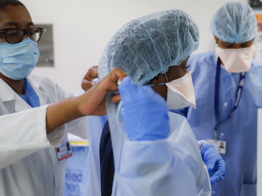 In this May 27, 2020 file photo, medical personnel adjust their personal protective equipment while working in the emergency department at NYC Health + Hospitals Metropolitan in New York.