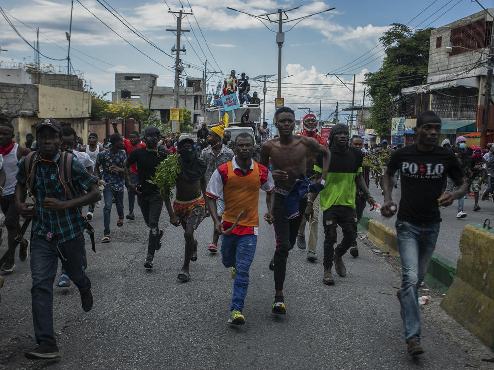 Protesters calling for the resignation of Haitian Prime Minister Ariel Henry run after police fired tear gas to disperse them in the Delmas area of Port-au-Prince, Haiti, Monday, Oct. 10, 2022.