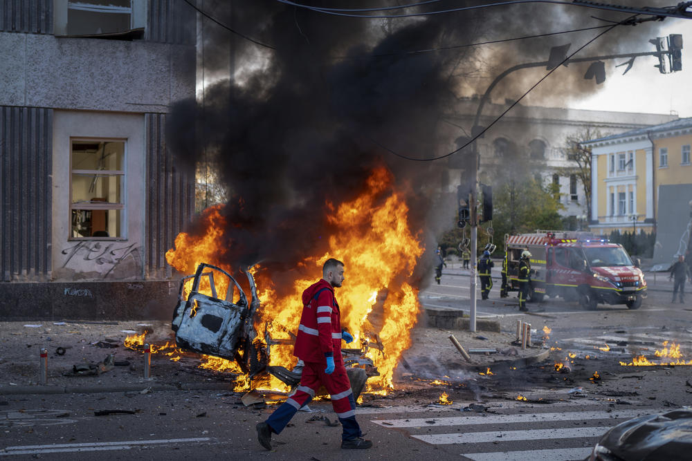A medical worker runs past a burning car after a Russian attack in Kyiv. Russia has many non-nuclear drones and missiles capable of hitting far behind the front lines.