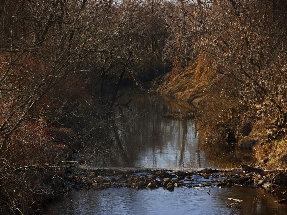 Water flows in Coldwater Creek on Thursday, Dec. 9, 2021, behind a row of homes at Belcroft Drive and Old Halls Ferry Road in Missouri's St. Louis County. Environmental investigation consultants have found significant radioactive contamination at an elementary school, which sits in the flood plain of Coldwater Creek which was contaminated by nuclear waste from weapons production during WWII.