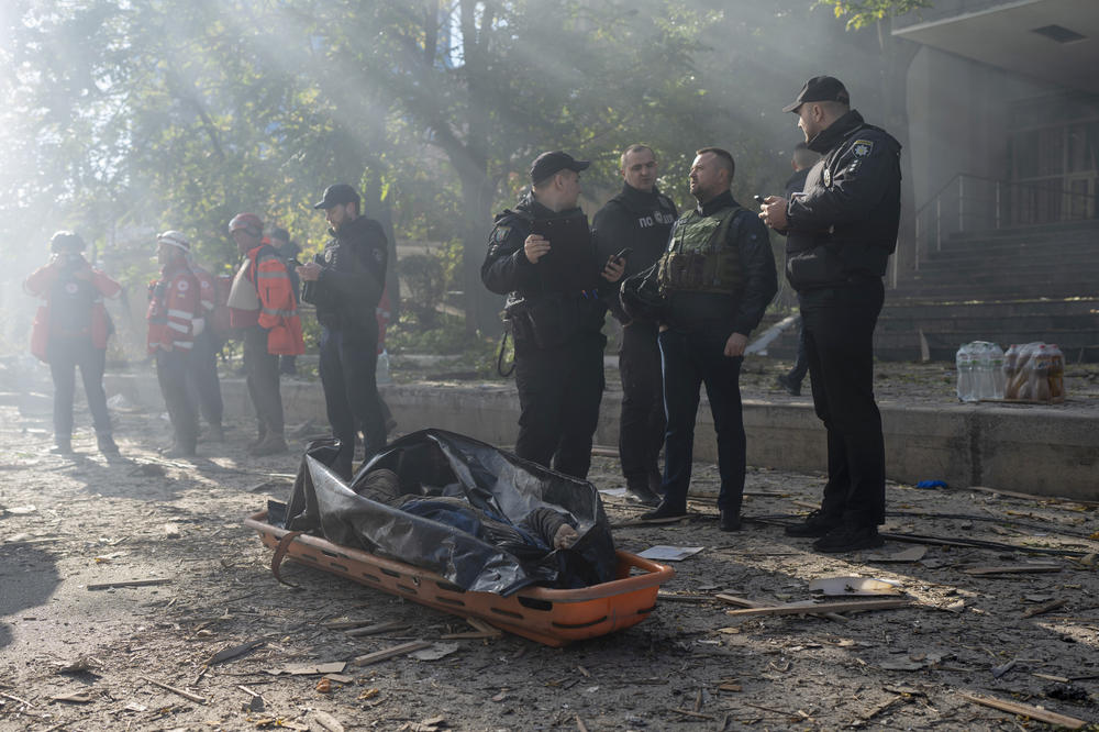 Police officers stand next to the body of a man killed after a drone fired on buildings in Kyiv. Waves of explosive-laden suicide drones struck Ukraine's capital early Monday, the blasts echoing across the city, setting buildings ablaze and sending people scurrying to shelters.