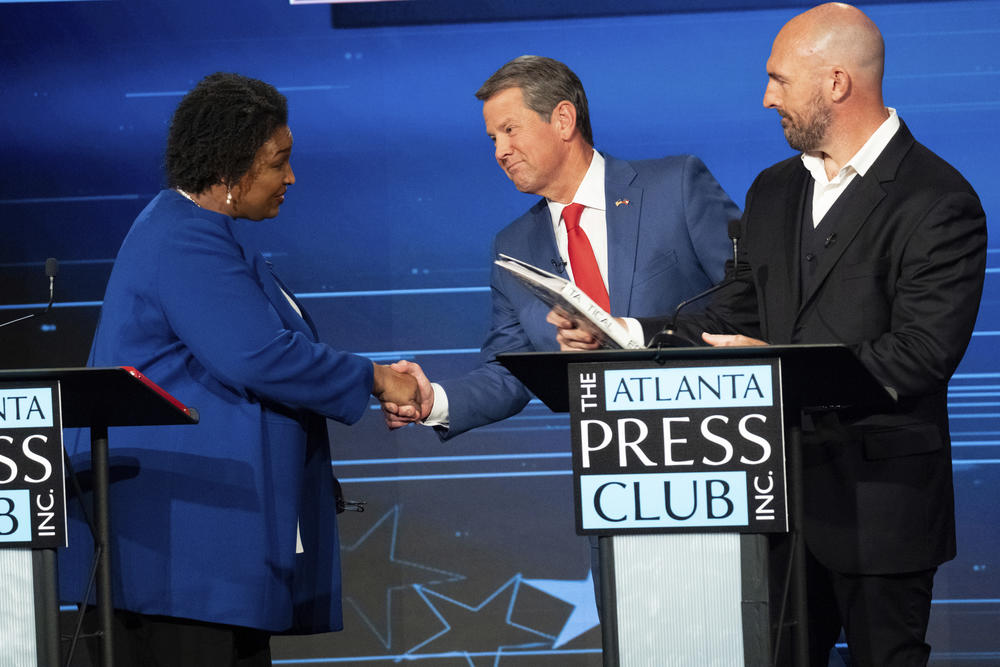 Democratic challenger Stacey Abrams, left, shakes hands with Georgia Republican Gov. Brian Kemp. Libertarian challenger Shane Hazel stands at right following the Atlanta Press Club Loudermilk-Young Debate Series in Atlanta on Monday.