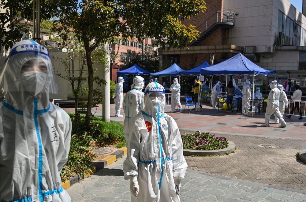 Workers and volunteers look on in a compound where residents are tested for COVID-19 during the second stage of a pandemic lockdown in Jing'an district in Shanghai on April 4.