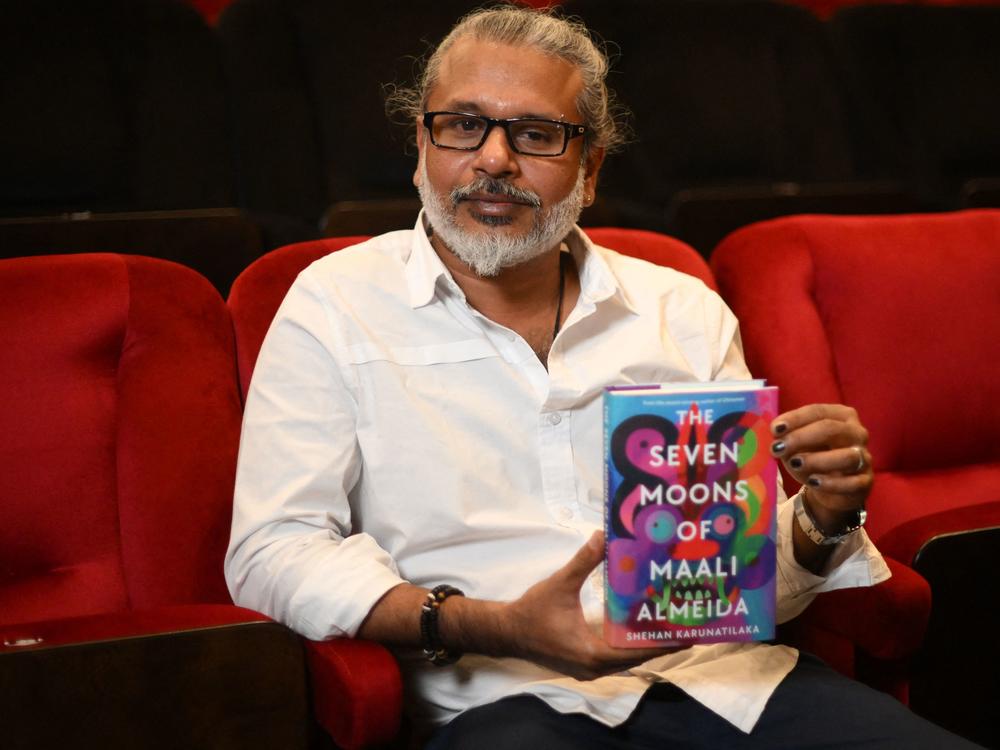 Sri Lankan author Shehan Karunatilaka holds his book <em>The Seven Moons of Maali Almeida</em> at the Shaw Theatre in London on Oct. 14. On Monday, his novel won the 2022 Booker Prize.