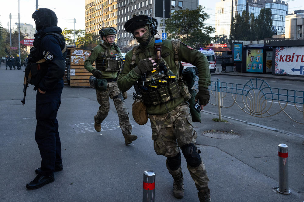 Ukrainian military members run for cover during an attack from 