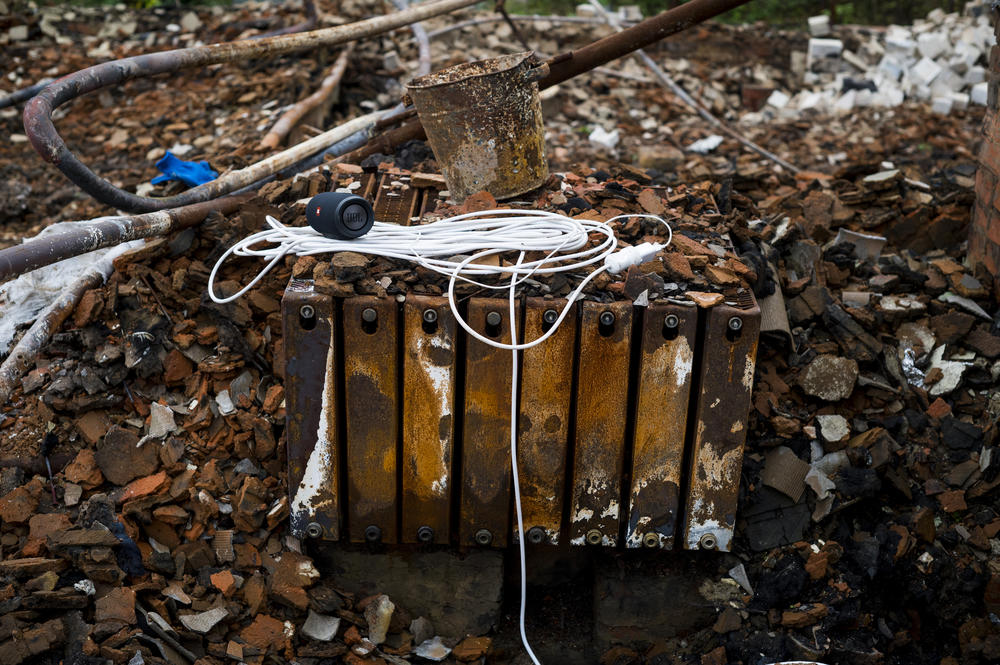 A portable speaker and an extension cord rest on a heater in the rubble of a home in Kolychivka on Oct. 1.