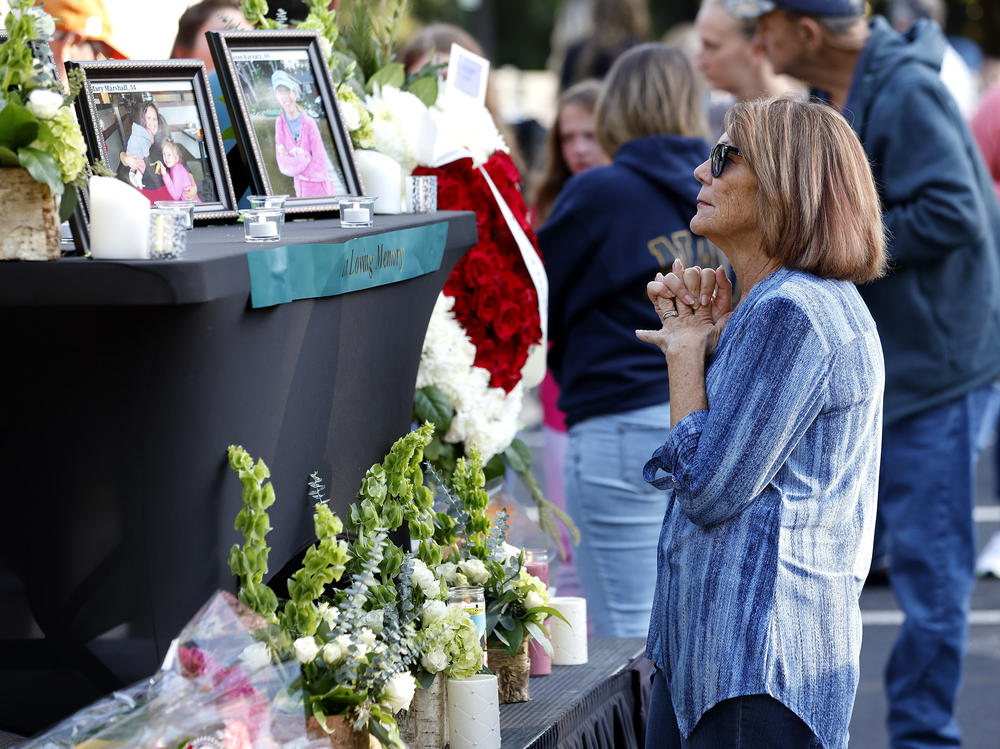 A woman stands before a photo of Raleigh shooting victim Susan Karnatz at a makeshift memorial.