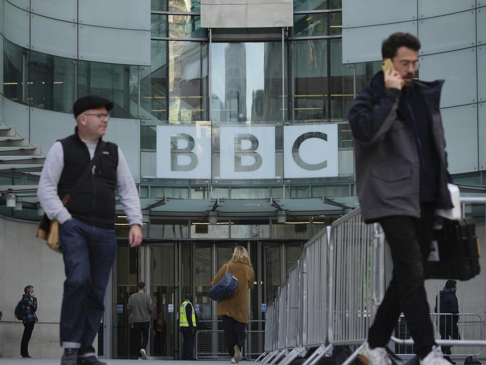 People walk past the BBC Headquarters in London on Tuesday as the BBC is celebrating 100 years of broadcasting.
