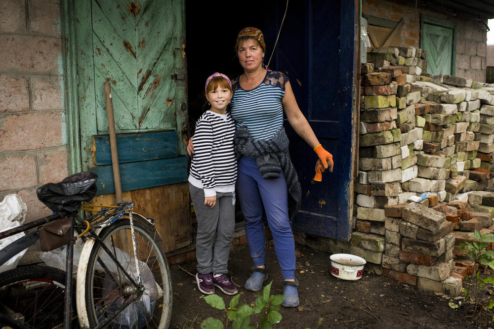 Tetiana Vereshchahina and her daughter Anastasiia, 9, stand next to a destroyed home owned by their family in Kolychivka.