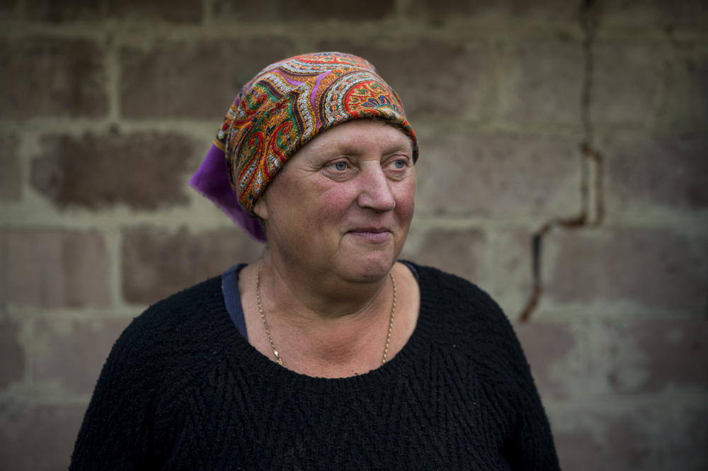 Kateryna Yurchenko, 60, stands near what remains of her lifelong home as volunteers work to clean it up in Kolychivka, seven months after it was destroyed on March 9.