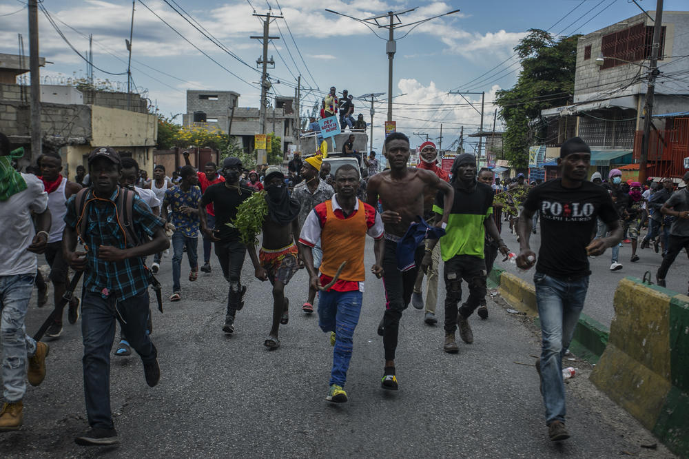 Protesters calling for the resignation of Haitian Prime Minister Ariel Henry run after police fired tear gas to disperse them in the Delmas area of Port-au-Prince on Oct. 10.