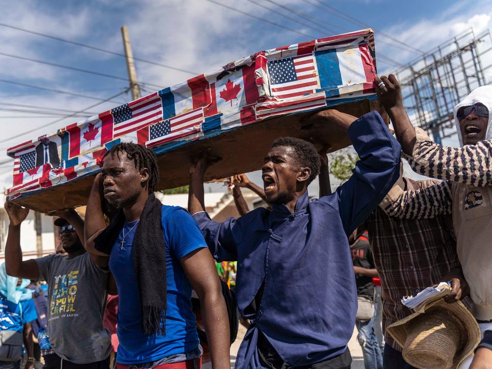 Demonstrators carry a coffin covered with American, Canadian and French flags and pictures of politicians as they protest on Jean-Jacques Dessalines Day in Port-au-Prince on Monday. Haitians protest against their prime minister and foreign countries as the nation celebrates the 216th anniversary of the assassination of Dessalines, a Haitian independence hero and founding father.