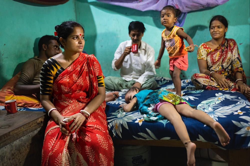 Pramila Giri and her husband left their village of Pathar Pratima in northeastern India after the changing climate made life — and farming — difficult. They migrated to the city of Gurgaon in 2011. Above: Giri (in red) spends time with her family and next-door neighbors during her day off from work as a cook.