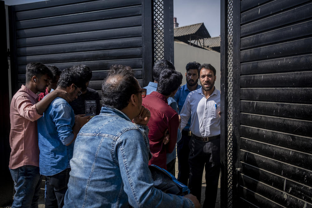 Students from the National Institute of Technology Srinagar talk to a security guard as they wait to enter the newly opened multiplex in Srinagar on Oct 1.