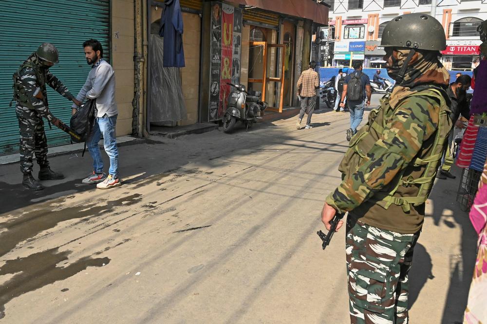 An Indian paramilitary trooper checks a man's bag during a random search along a street in Srinagar on Tuesday.
