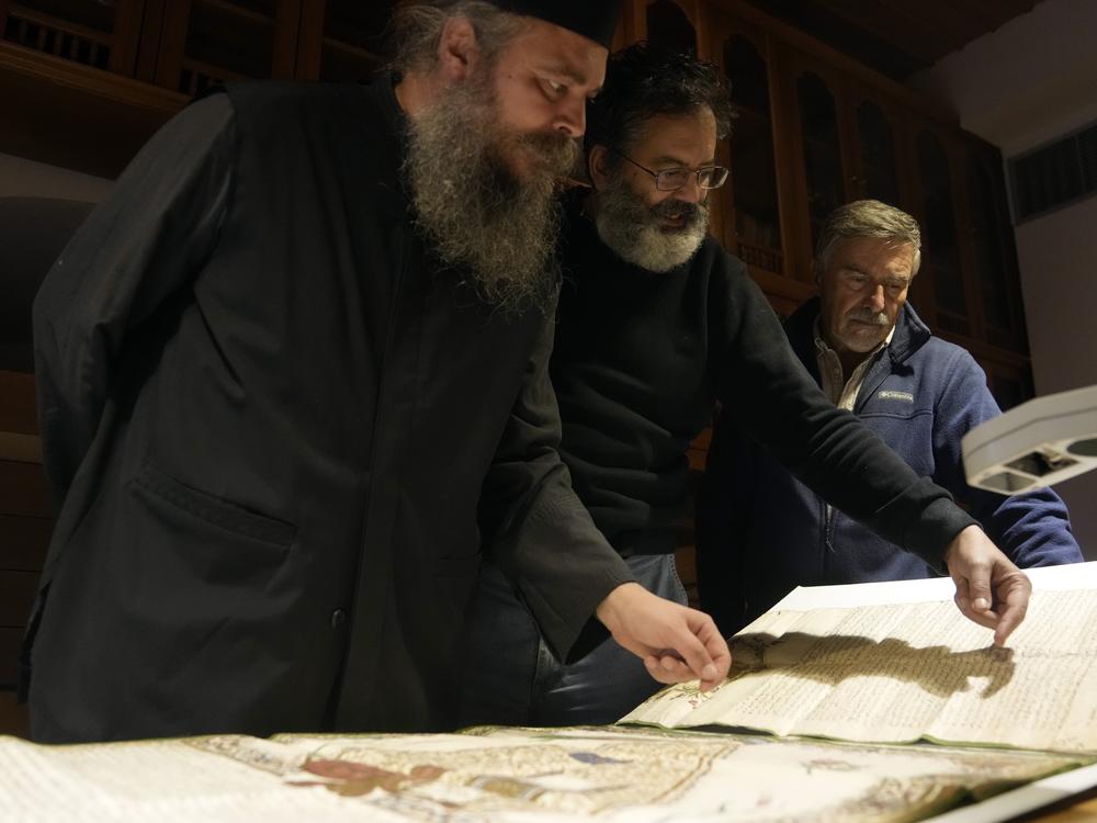 Father Theophilos, a Pantokrator monk, left, checks a manuscript at the library of Pantokrator Monastery in the Mount Athos, northern Greece, on Thursday, Oct. 13, 2022.