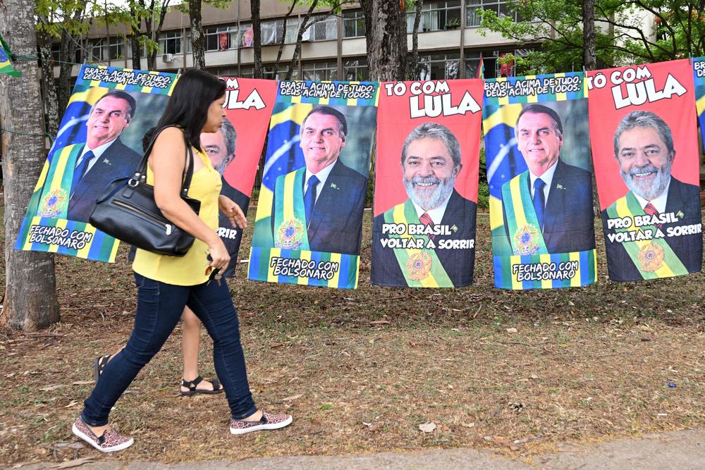 A woman walks past towels with the images of former Brazilian President Luiz Inacio Lula da Silva and incumbent Brazilian President Jair Bolsonaro on the street in Brasilia on Oct. 21.