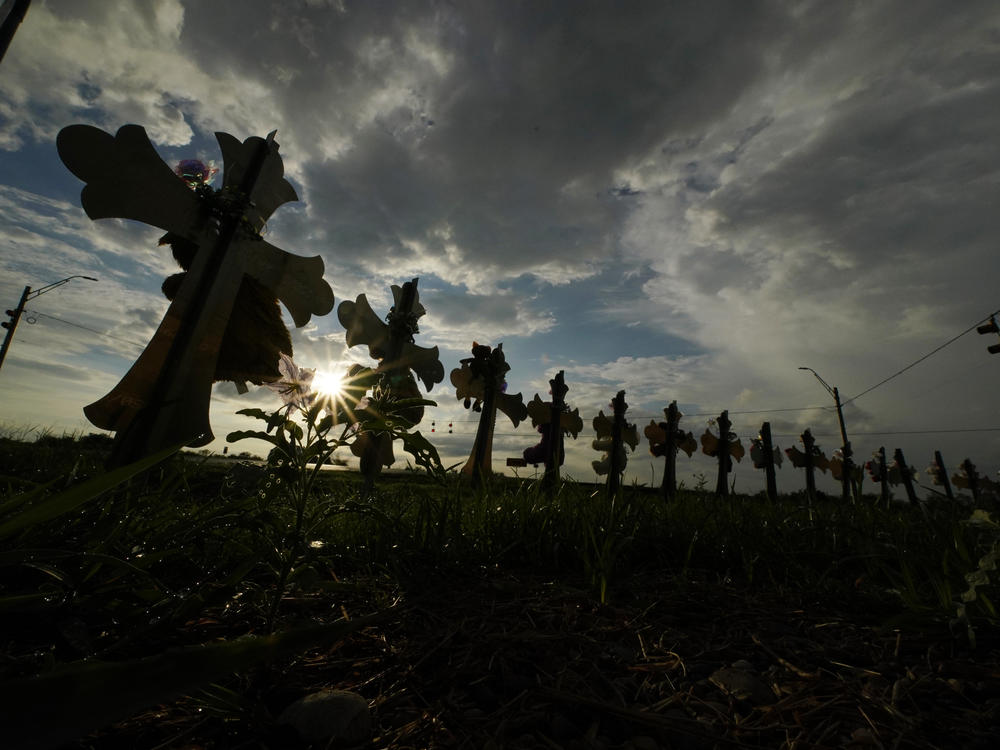 Vehicles on Aug. 25, 2022 pass crosses placed to honor the victims of the shootings at Robb Elementary School in Uvalde, Texas.