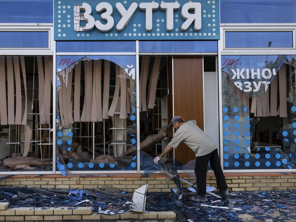 A man clears pieces of glass from his shop on Oct. 1 in Kupiansk, Ukraine, after the city was liberated from Russian occupation.