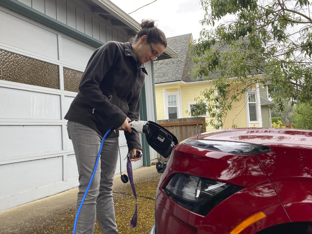 Rebecca DeWhitt charges her electric vehicle in the driveway of the Portland, Ore., home she rents on Sept. 30.