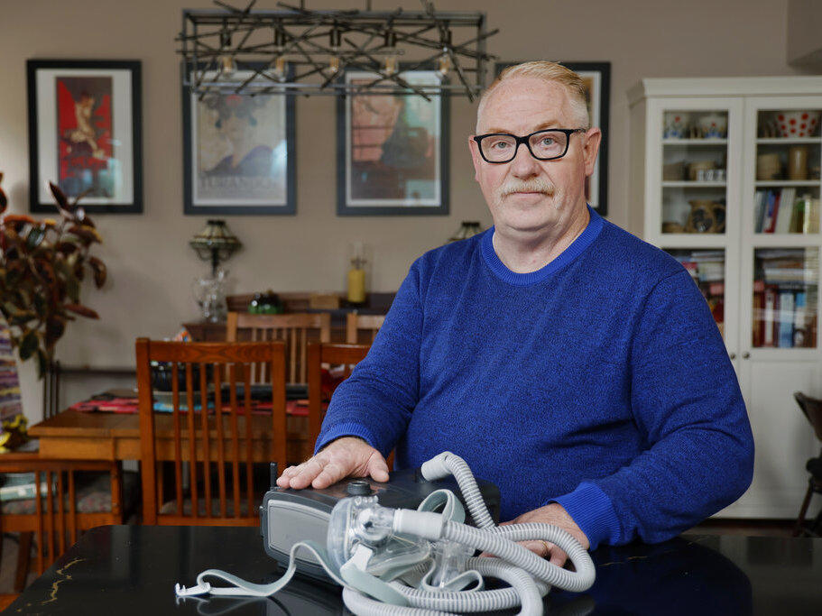 Jeffrey Reed, who experienced persistent sinus infections and two bouts of pneumonia while using a Philips CPAP machine, poses with the device Oct. 20 at his home in Marysville, Ohio.