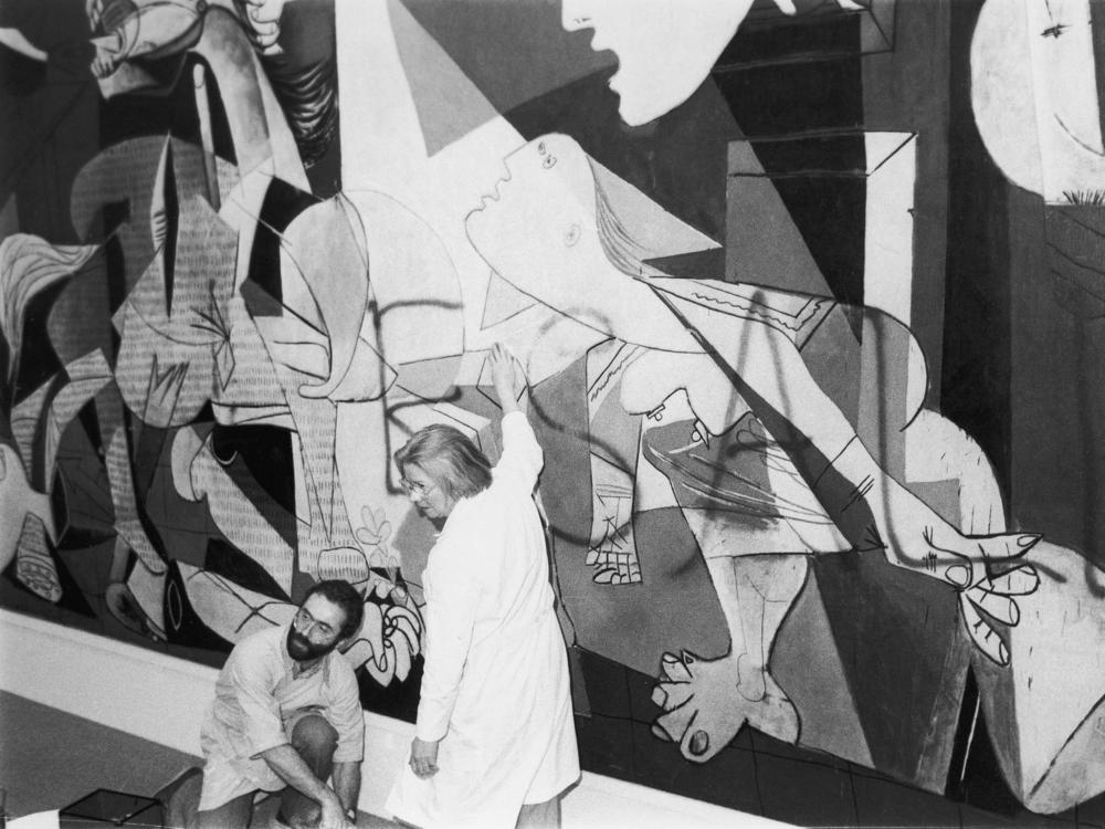 Museum of Modern Art employees clean spray paint off of Pablo Picasso's mural <em>Guernica</em> shortly after Tony Shafrazi wrote 