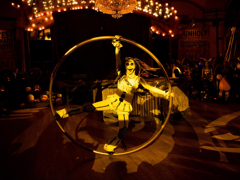 A performer swings around on a giant hula hoop as people cheer.