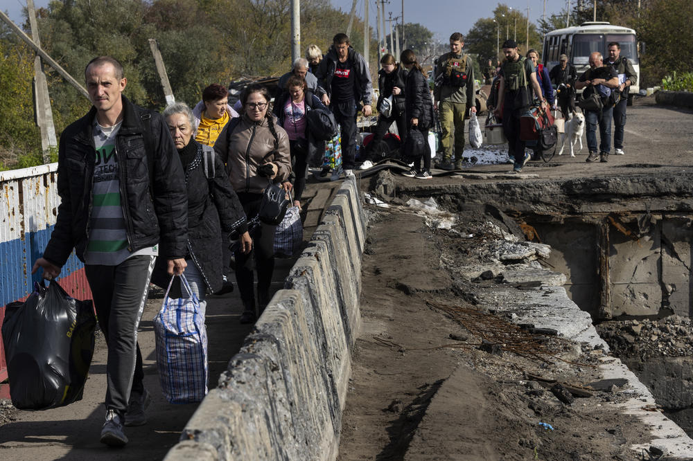 Refugees flee over a destroyed bridge in Kupiansk on Oct 1.