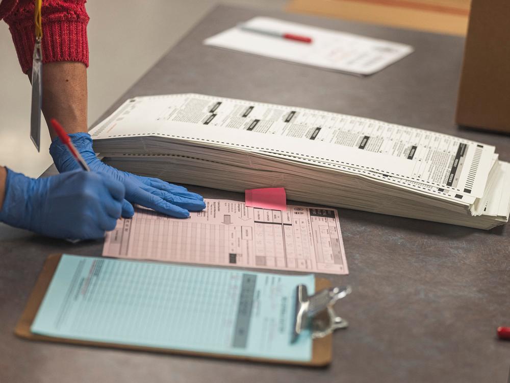 A poll worker handles ballots for the midterm election, in the presence of observers from both Democrat and Republican parties, at the Maricopa County Tabulation and Elections Center in Phoenix on Oct. 25.