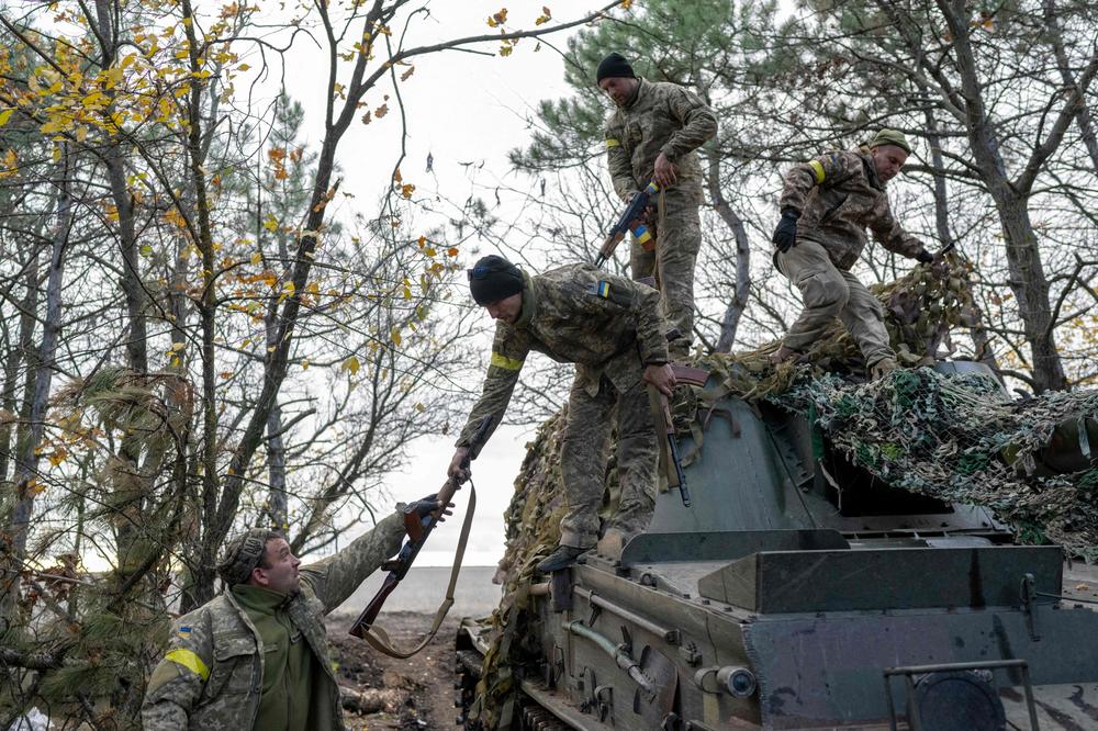 Ukrainian artillery unit members turn back to their position after firing toward Kherson on Friday.